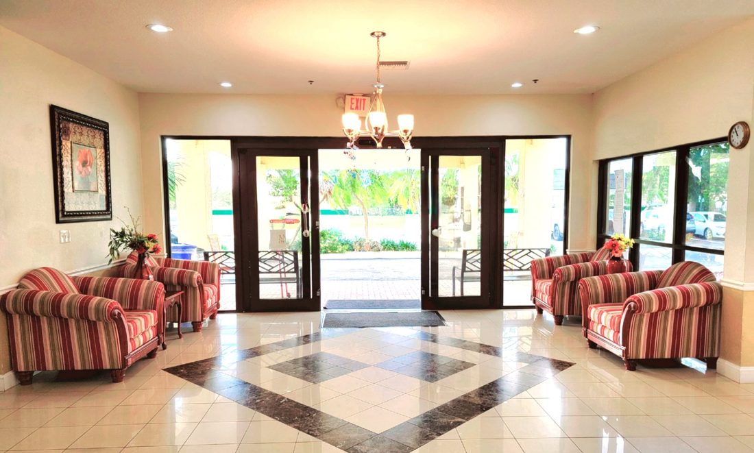 Front lobby with striped armchairs, glass doors and a tiled floor at Sunny Hills in Homestead